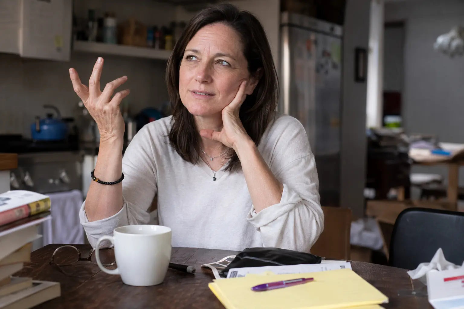 Woman pausing mid-sentence at a kitchen table, searching for a word