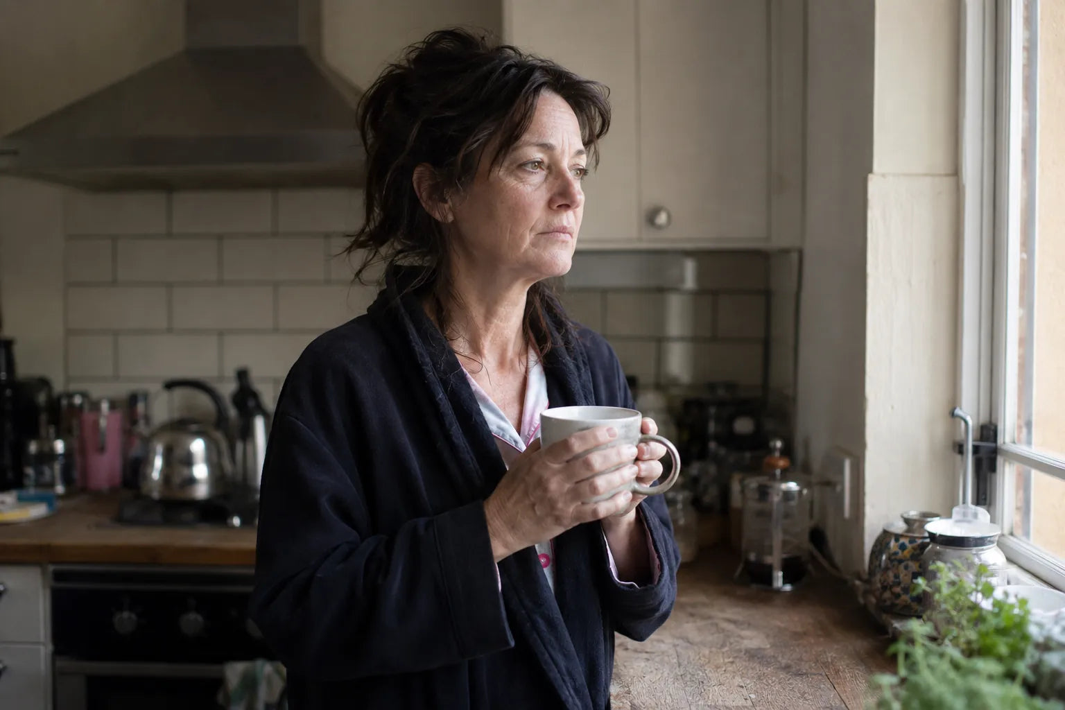Woman at the counter with a second coffee, staring out the window